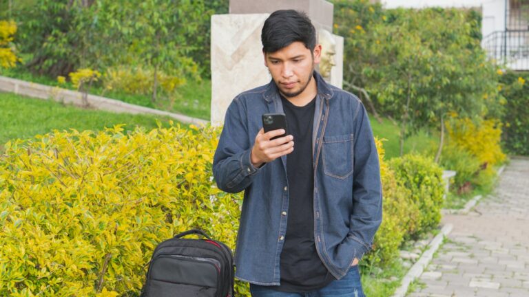 5GB to 12GB SIM Only Plans for a Second Phone on Your Travels Traveller checking his phone with his bag beside him