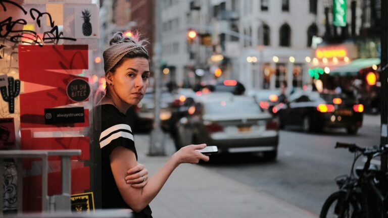 Woman hailing a taxi on a busy city street