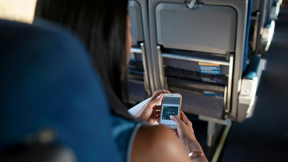Traveller checking a smartphone in a plane seat