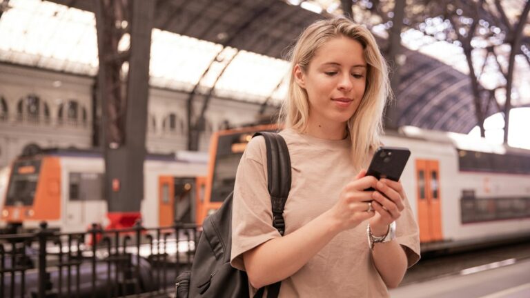 Traveller with a backpack checking her phone at a station