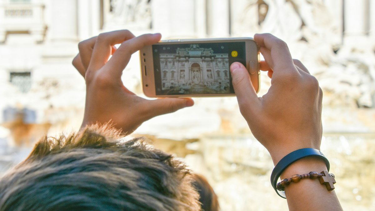 Tourist photographing a Rome fountain with a smartphone