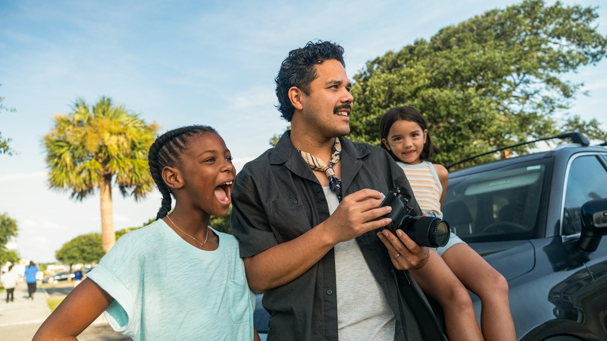 Father and two children laughing beside their car