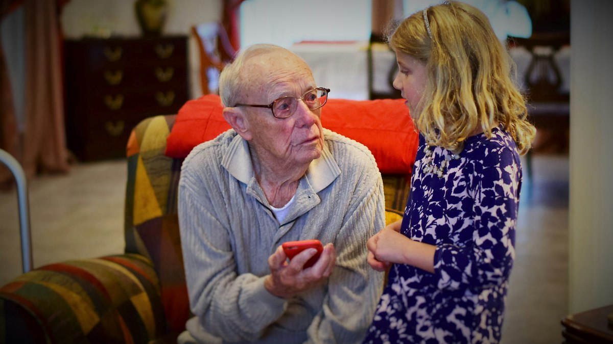 Grandfather and granddaughter looking at a phone together